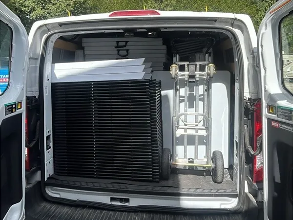 The back of our cargo van loaded with folding tables, stacked chairs, and a dolly for a New Westminster delivery