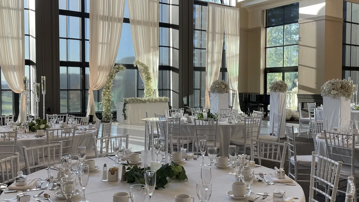 White Chiavari chairs around linen-covered round tables at a Swaneset Bay wedding reception. The club is in Pitt Meadows.