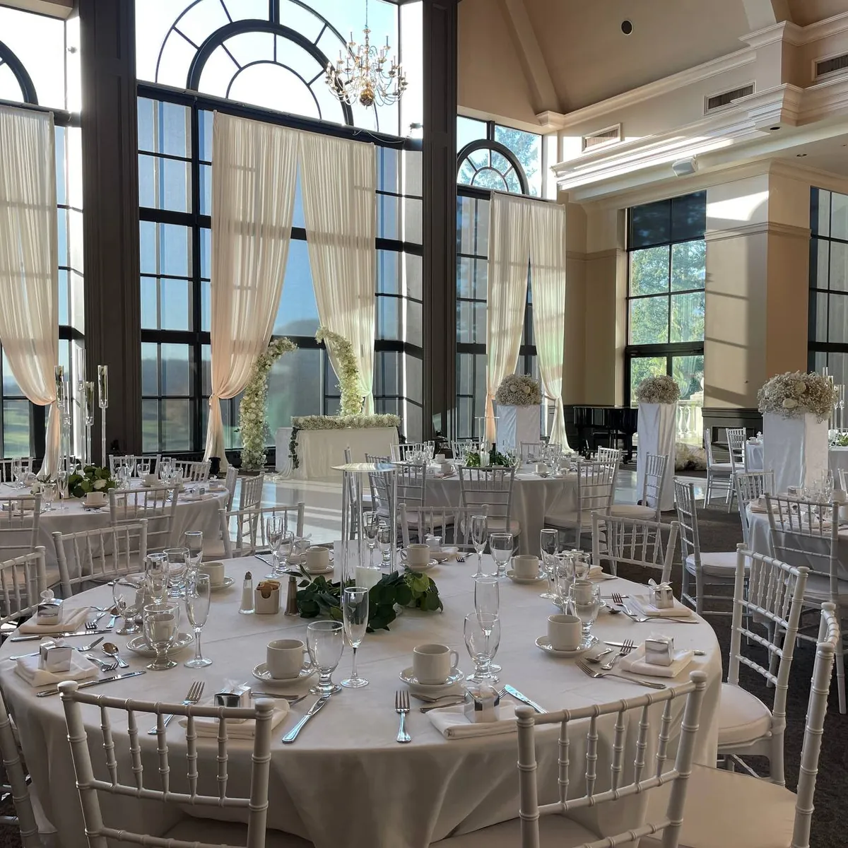 White Chiavari chairs around linen-covered round tables in the Swaneset Bay ballroom, Pitt Meadows