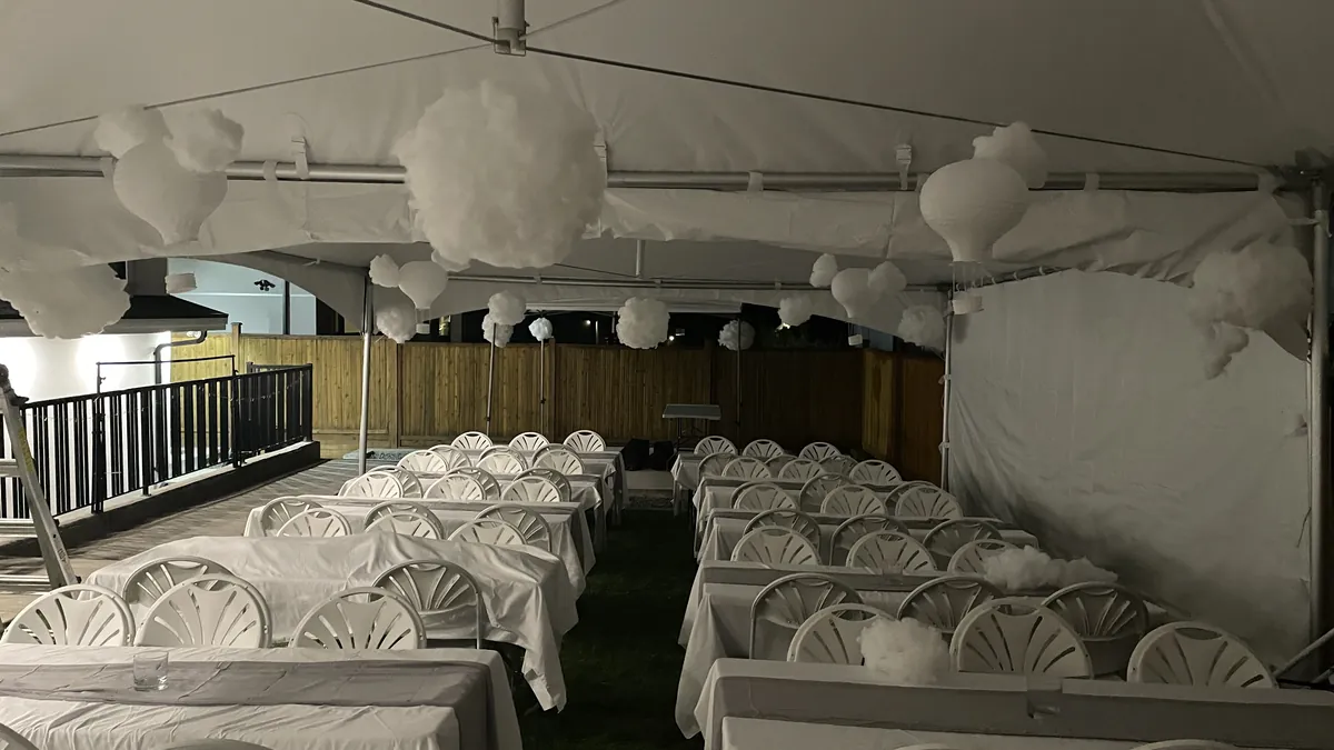 Night backyard tent in Surrey with banquet tables, white fanback chairs, and cloud lanterns in the peaks