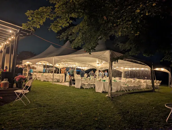 Backyard wedding tent rental at night with string lights