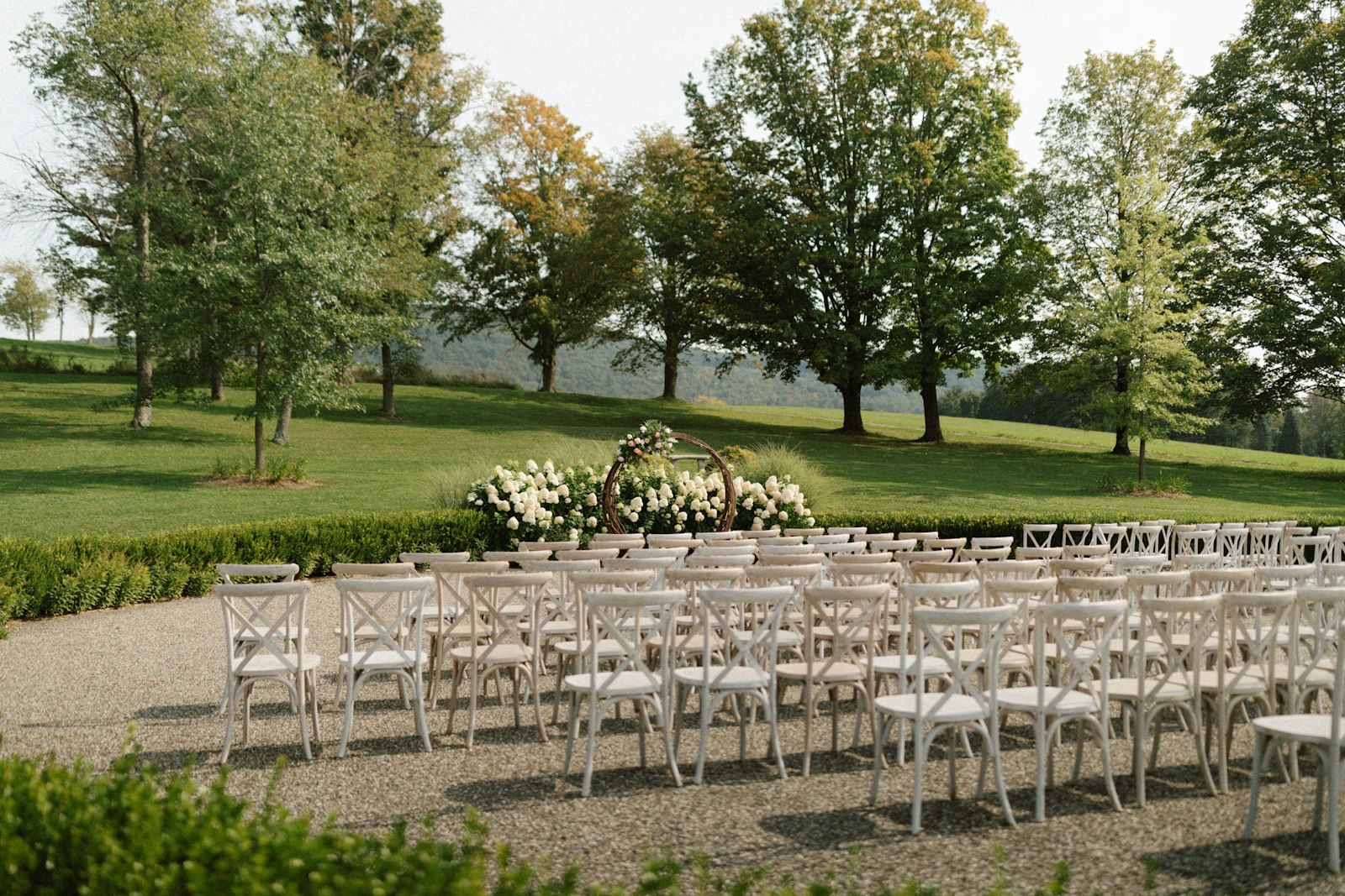 Rows of white ceremony chairs facing an altar at an outdoor wedding