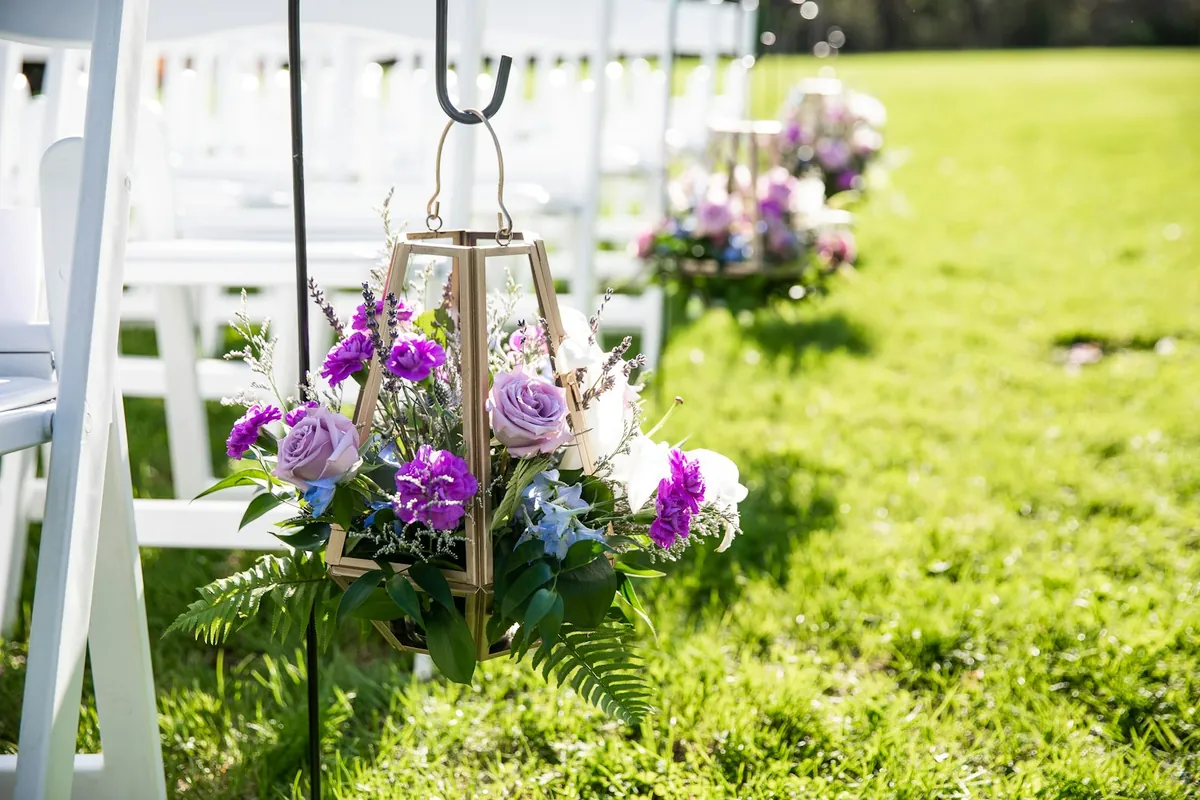 Rows of white ceremony chairs at an outdoor wedding setup