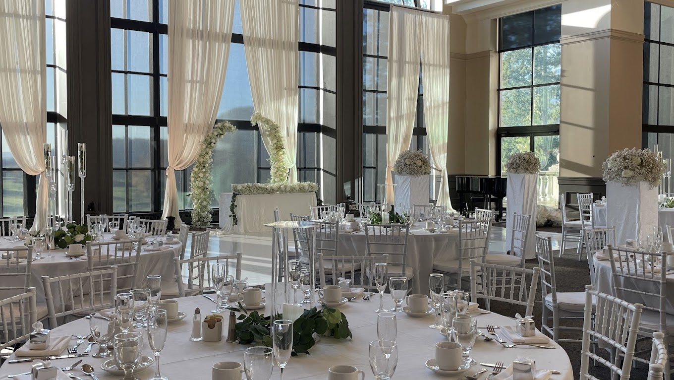 A row of clean white Chiavari chairs lined up on grass at an outdoor wedding ceremony