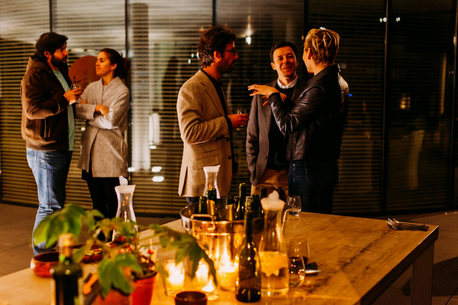 Cocktail-hour highboy tables set up outdoors with guests in conversation behind them