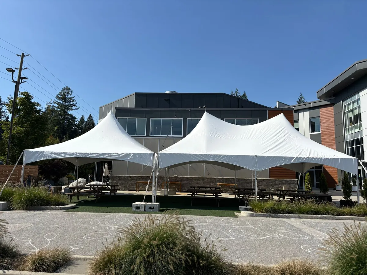 Two high-peak frame tents covering picnic tables in an office courtyard