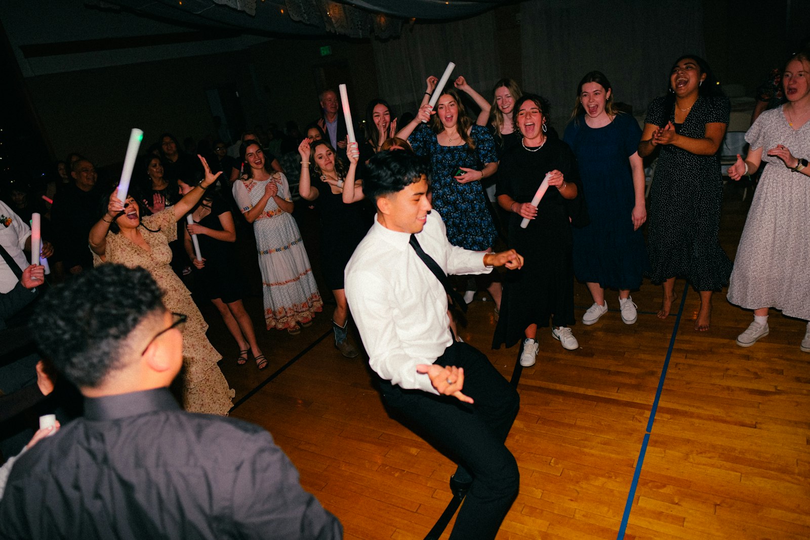 A group of people on a dance floor at a wedding reception with festive party energy