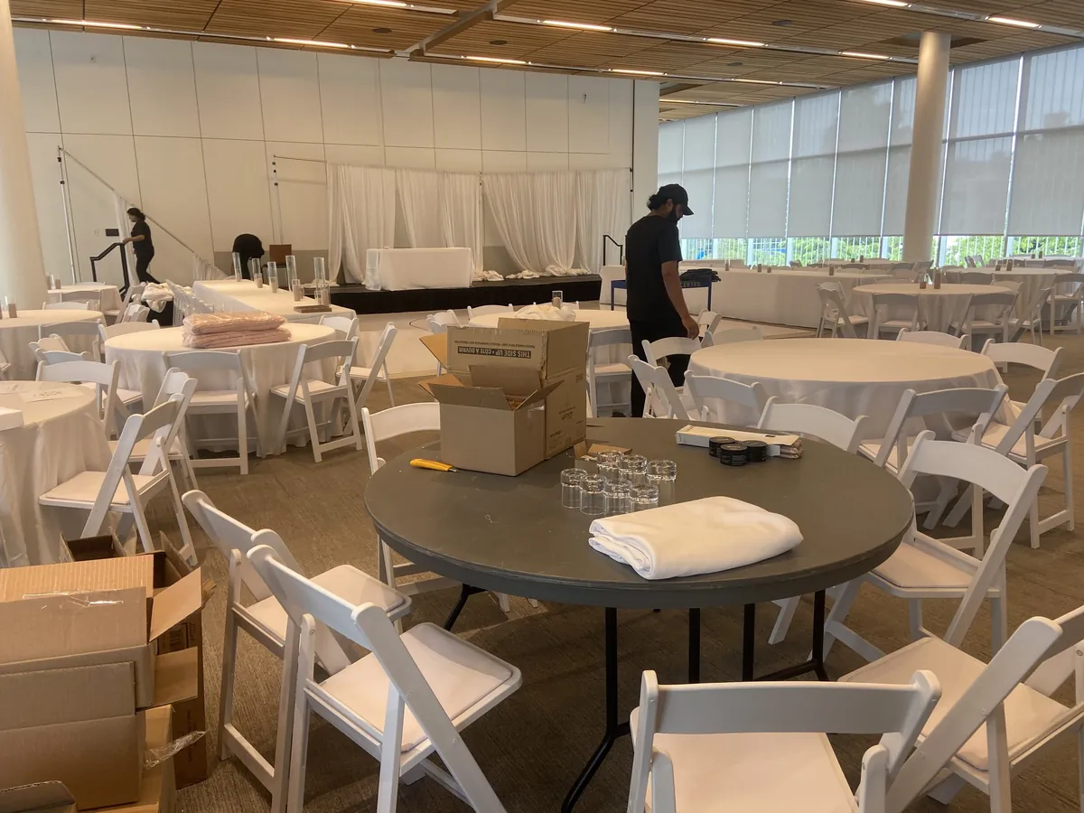 Our crew staging round tables and white resin folding chairs during a venue setup