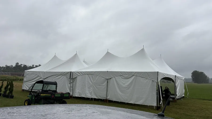 Event tents staked on a farm field in the rain ahead of an event