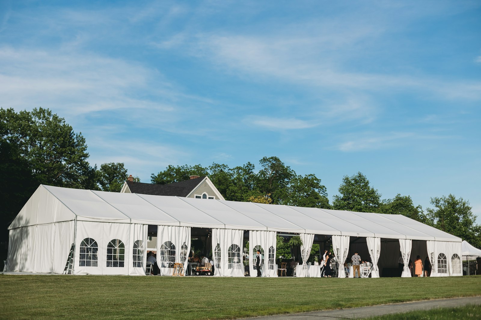 A wide white marquee tent staged on open lawn — the standard footprint for Westham Island farm receptions